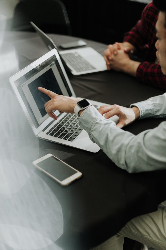 Person pointing to something on a laptop screen while sitting with another person