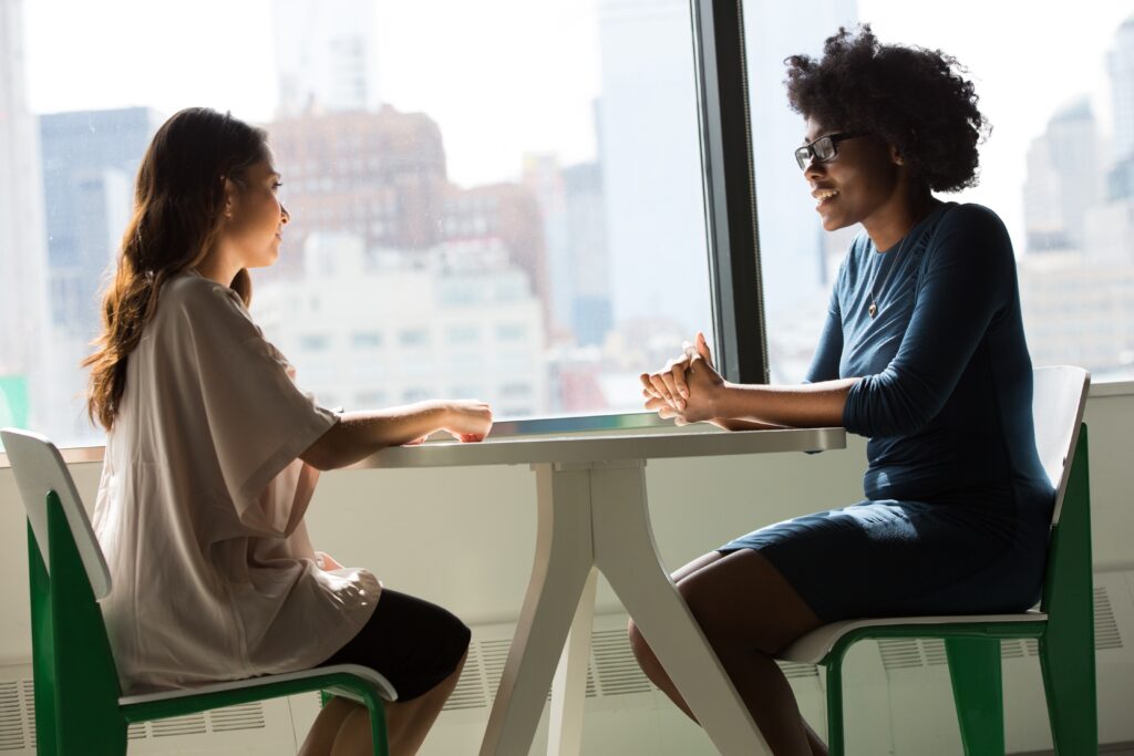 Two women sitting down talking at a round table in a city office