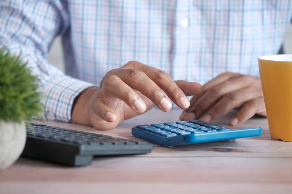 Person in dress shirt working on a calculator at their desk