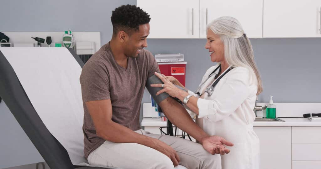 Mature white female physician checking male patients blood pressure at clinic