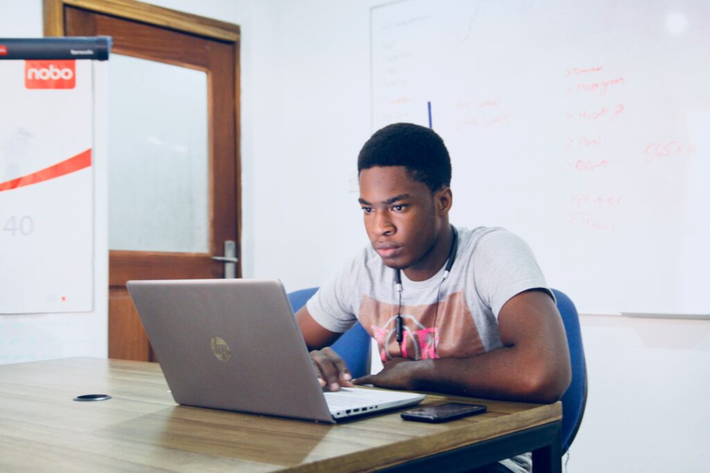 A young man sitting in a classroom at an hp laptop