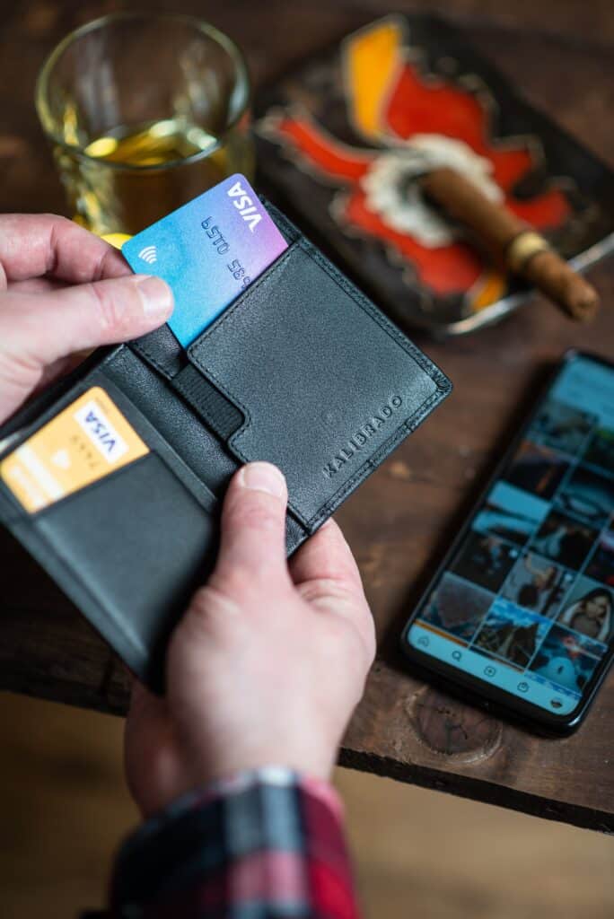 Hands pulling out a two-toned Visa card from a black wallet