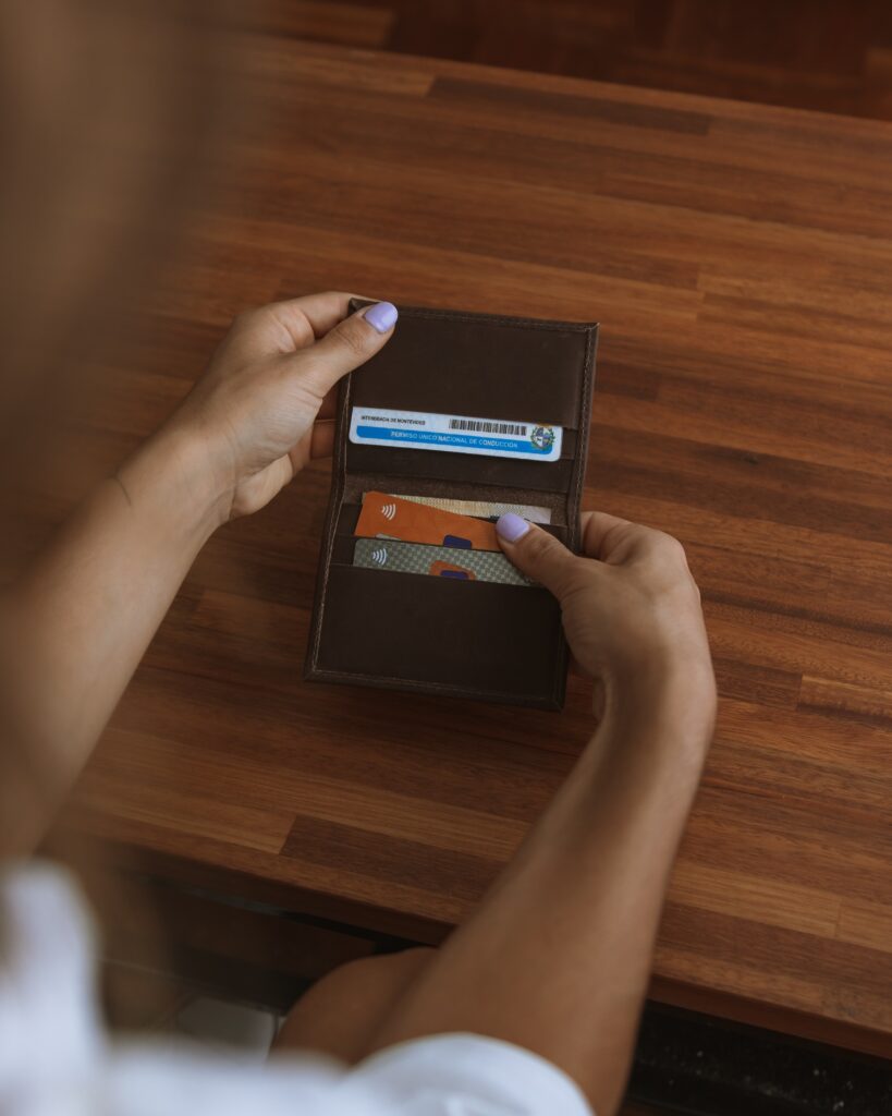 Hands holding a brown wallet with cards showing