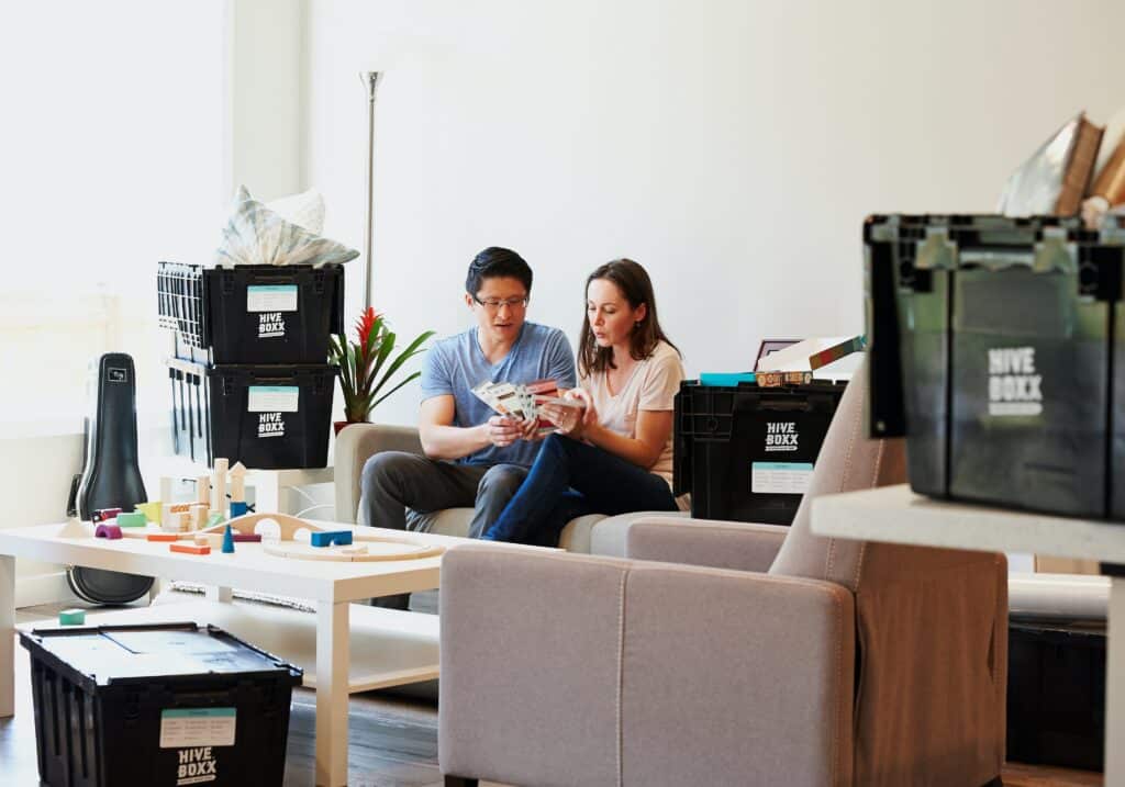 Man and woman looking through a pile of tickets while sitting on the couch surrounded by Hive Boxxes