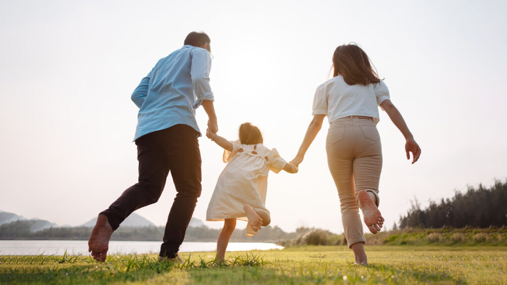 A family runs and plays together in a field.