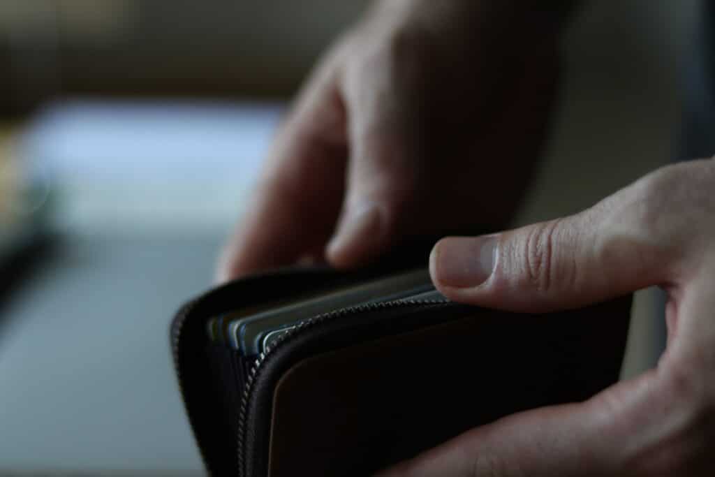 Hands opening a zippered wallet with multiple cards inside