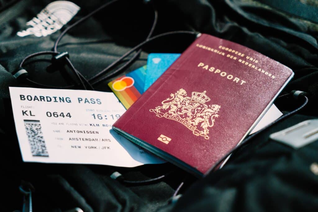 Boarding pass, passport and cards laying on top of a black backpack