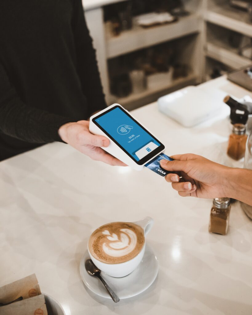 Hand inserting Visa card into a card reader at a coffee shop