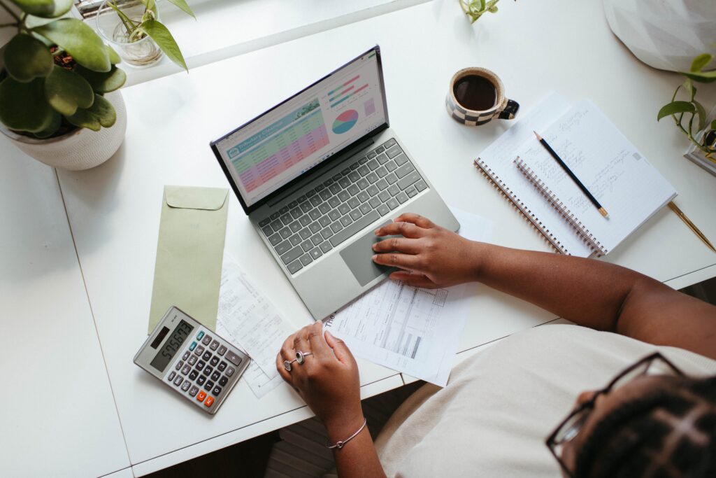 Woman looking at different graphs and charts on her laptop while sitting at a desk