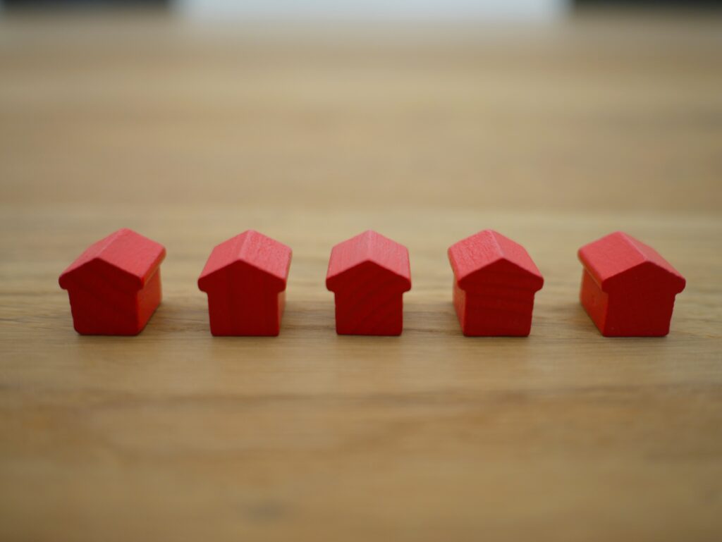 5 small red wooden block houses lined up on a table