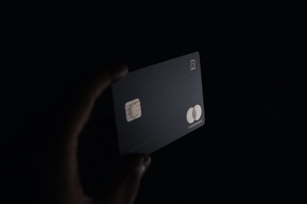 Hands holding a Mastercard in front of a black background