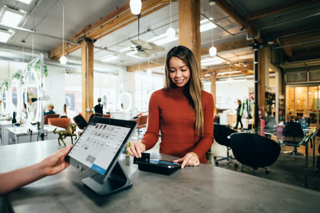 Woman swiping her card at a salon front desk