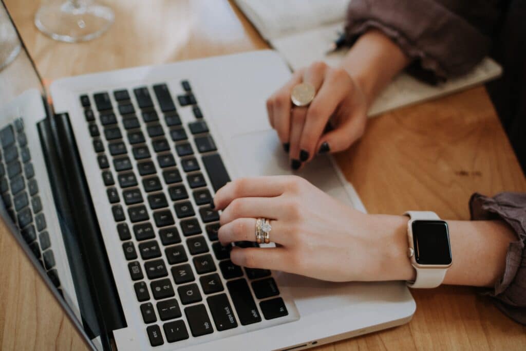 Woman's hand with rings and Apple watch typing on an Apple laptop