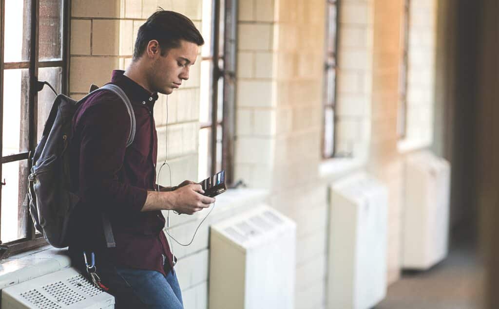 Student with backpack in hallway with headphones on