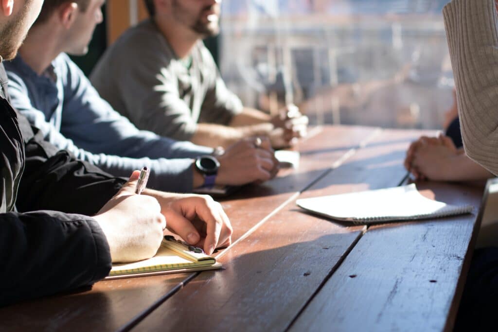 A group of people discussing around a table with a few notepads