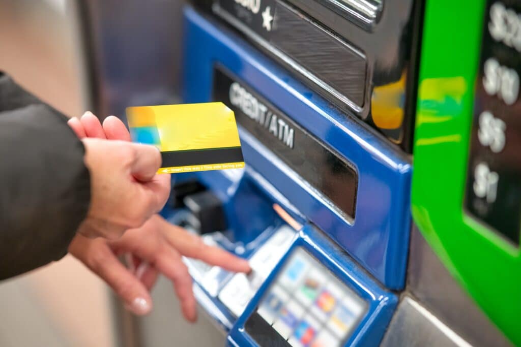 Person retrieving a card from a machine that says "Credit/ATM"