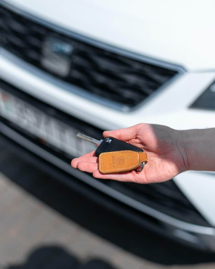 Hands holding car keys in front of car