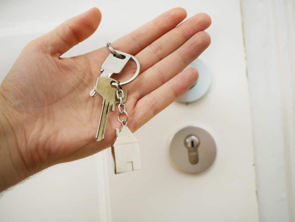 Hands holding house keys in front of a front door