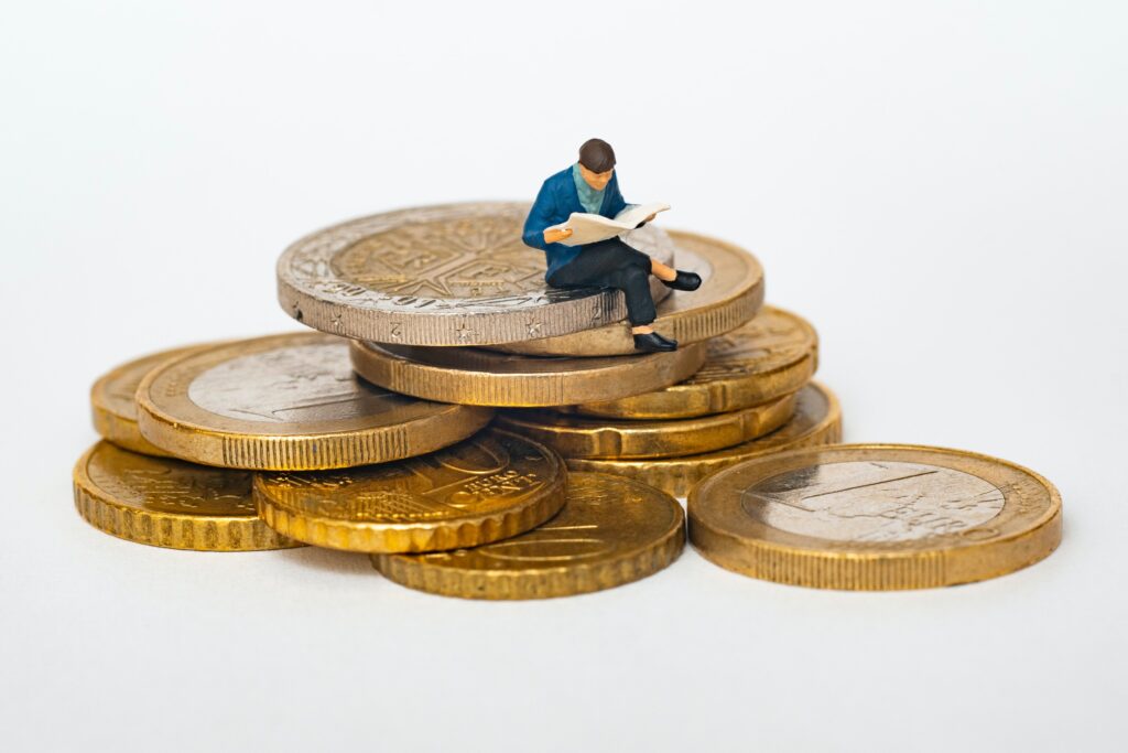 Small figurine sitting on top of a handful of gold coins