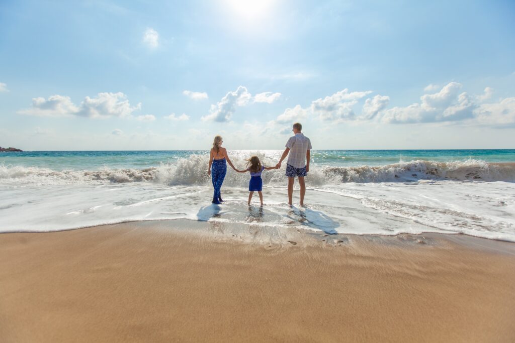 Mom, dad and young daughter holding hands in the ocean