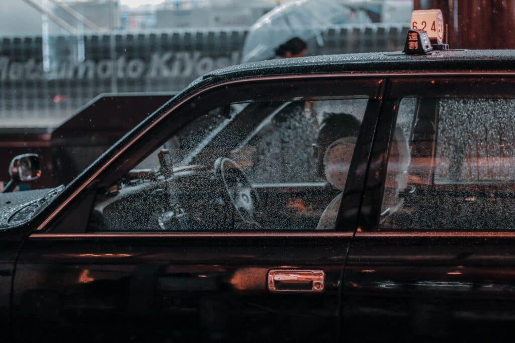 Person driving an old black car in a rain storm