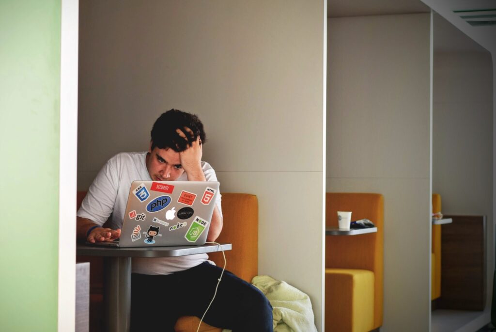 Stressed student working on a laptop while sitting in a booth