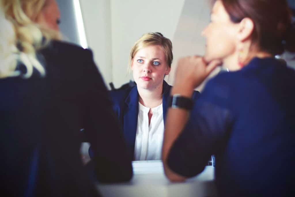 Young blonde woman meeting with two other women in an office setting