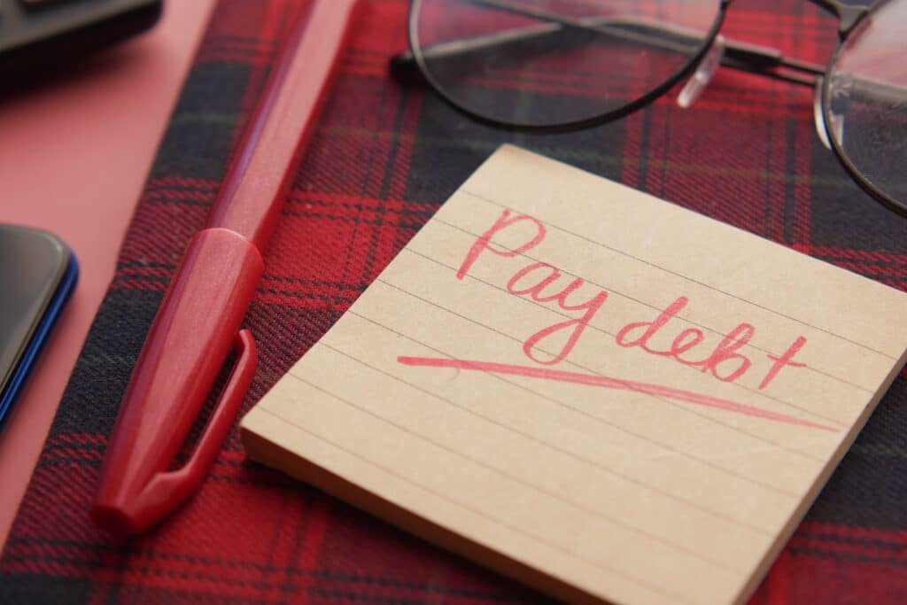 Sticky note pad that says Pay debt in red