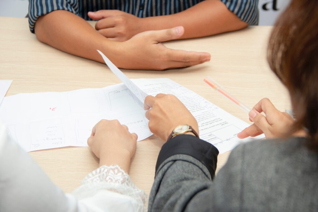 Two people sitting opposite of a third person while looking over documents