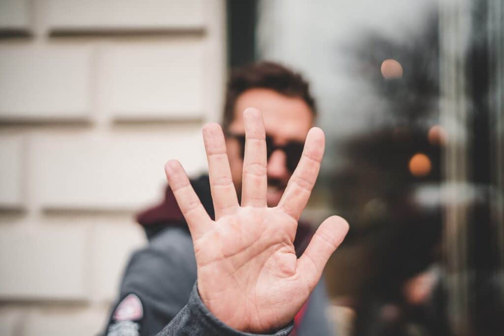 Man holding up full hand or 5 fingers as if to stay stop