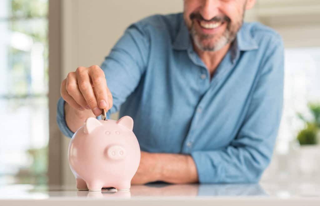 A man puts money in a piggy bank.