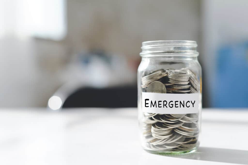 A jar labeled emergency with coins in it.