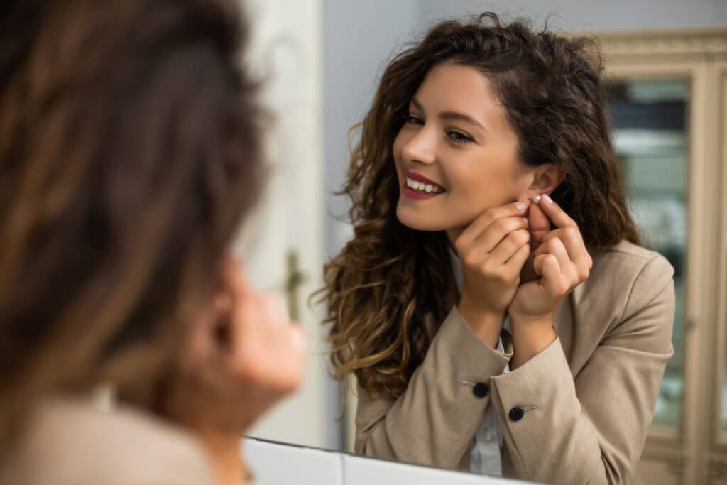 A woman puts on a pair of earrings