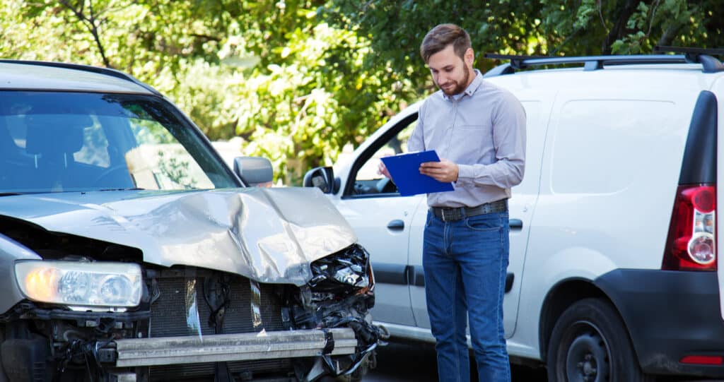 An insurance agent assesses damage on a vehicle.