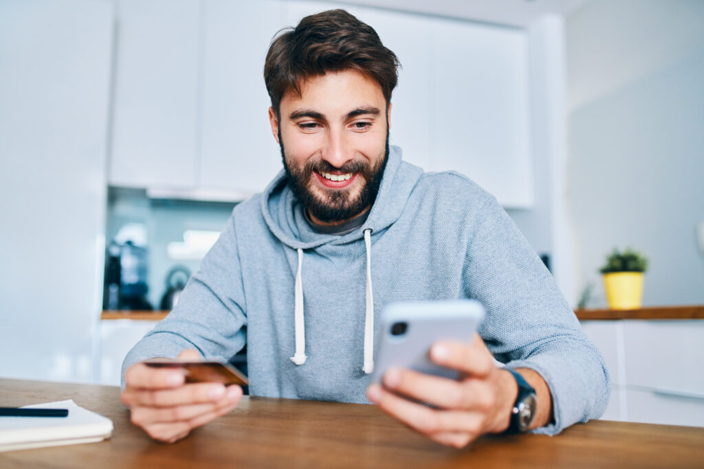 A man using his smartphone to manage his finances with a checking account. The best checking accounts of 2025 offer high interest rates, low fees, and top digital banking features.